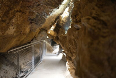 EN: Illuminated visitor pathway with railing inside a show cave