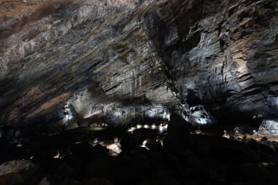 EN: Wide cave illuminated with even LED lighting and visitor area