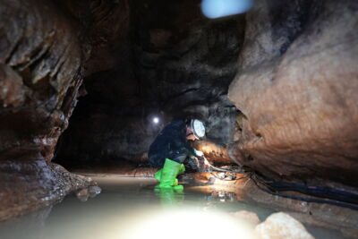 EN: Team installing lighting in a water-filled cave environment