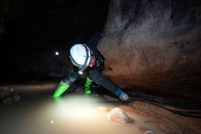 DE: Höhlenforscher mit Ausrüstung bei Arbeiten in einer beleuchteten Höhle